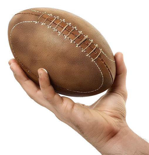 A hand holds a brown American football with visible white stitching against a black background, highlighting focus and control.